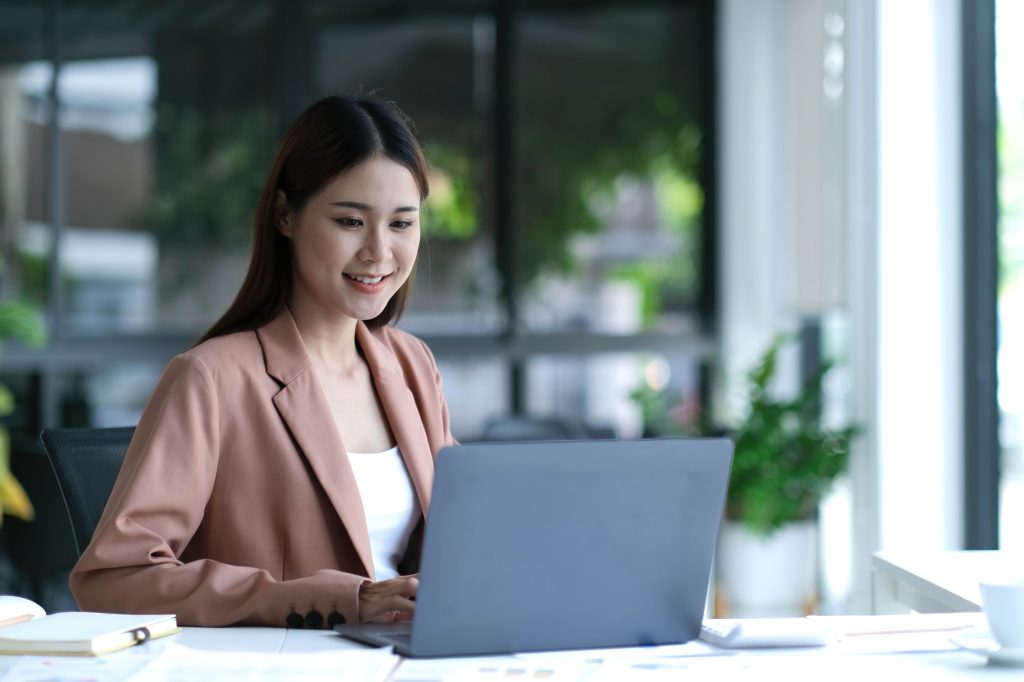 Charming asian businesswoman sitting working on laptop in office.